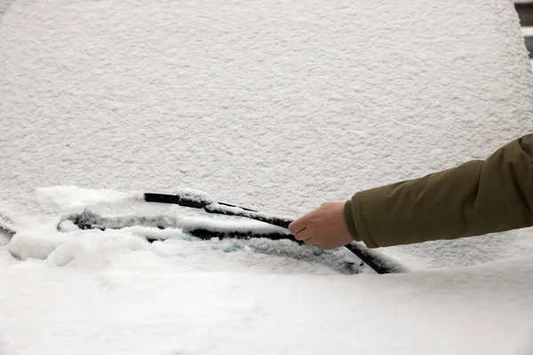 Woman cleaning car wiper blade covered with snow, closeup
