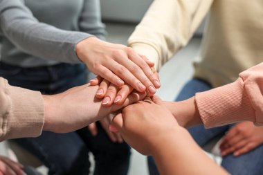 Group of people holding hands together indoors, closeup. Unity concept