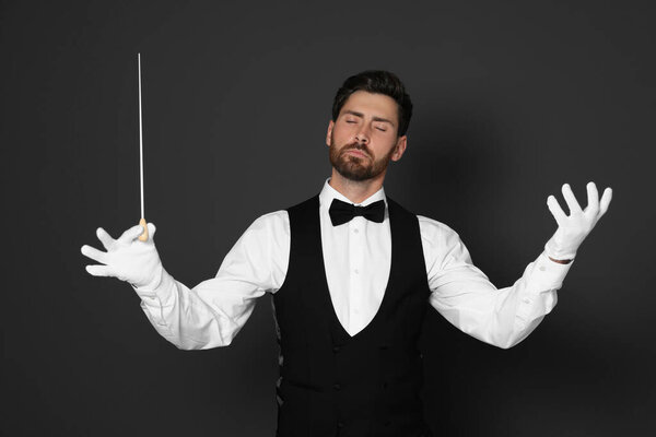 Professional conductor with baton on grey background