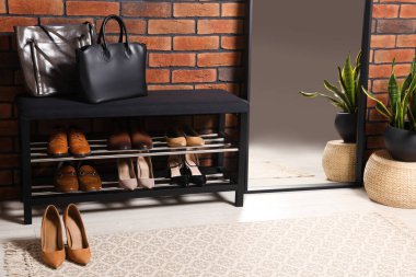 Ayakkabı depolama tezgahı ve tuğla duvarın yanında ayna olan şık bir koridor. İç tasarım