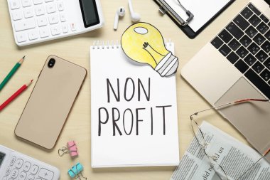 Kâr amacı gütmeyen. Ahşap masa üzerinde defter, kırtasiye ve kağıt lamba ile düz kompozisyon yatıyordu