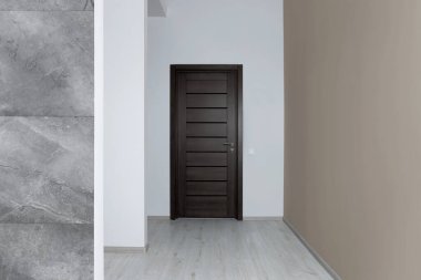 Duvarları ve siyah kapısı olan boş bir oda.