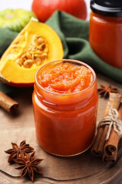 Kavanoz dolusu lezzetli balkabağı reçeli ve malzemeler fayanslı yüzeyde, yakın plan.