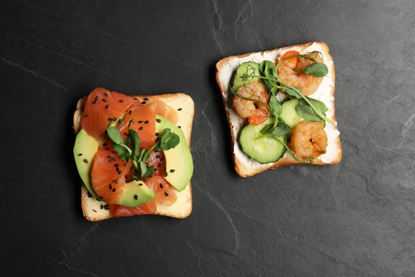 Tasty toasts with different toppings on black table, flat lay
