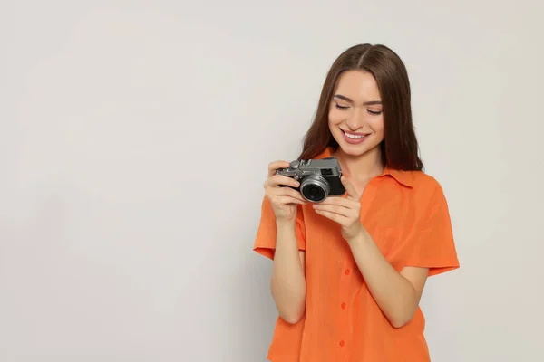 Young woman with camera on white background, space for text. Interesting hobby
