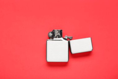 Kırmızı arka planda gri metalik sigara çakmağı, üst görünüm