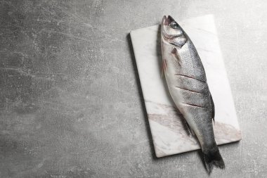 Açık gri masada taze çiğ levrek balığı, üst manzara. Metin için boşluk