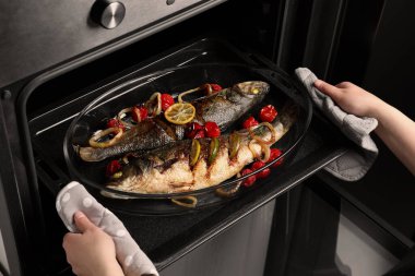 Deniz levreği ve fırından garnitür alan bir kadın, yakın plan.