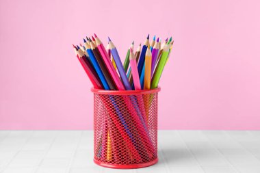 Pembe arka plana karşı çok sayıda renkli kalem var.