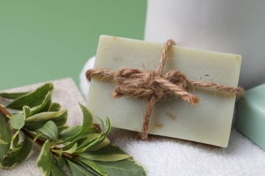 Sabun çubuğu, bitki dalı ve yeşil arka planda havlu, yakın plan.