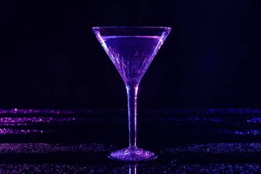 Koyu mavi arka planda neon ışıklı bir bardak martini.
