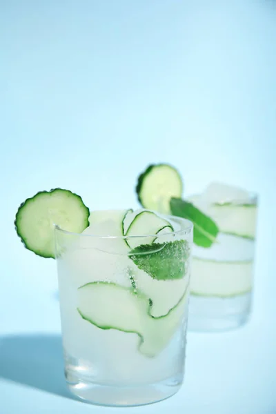 Tasty fresh cucumber water with mint on light blue background