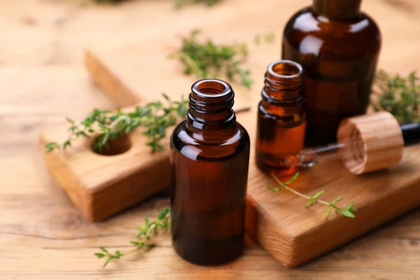 Thyme essential oil and fresh plant on wooden table