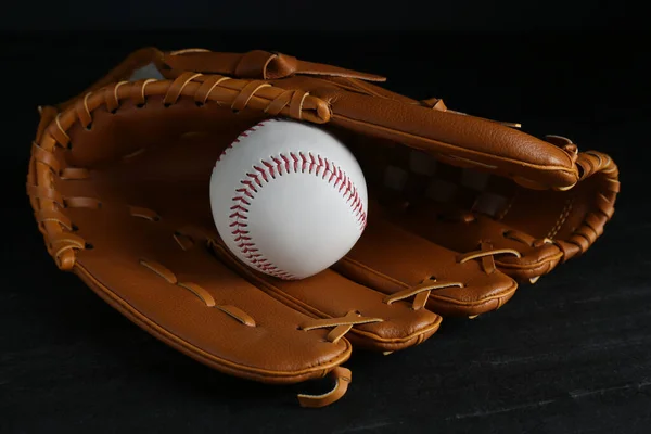 Catcher\'s mitt and baseball ball on black background. Sports game