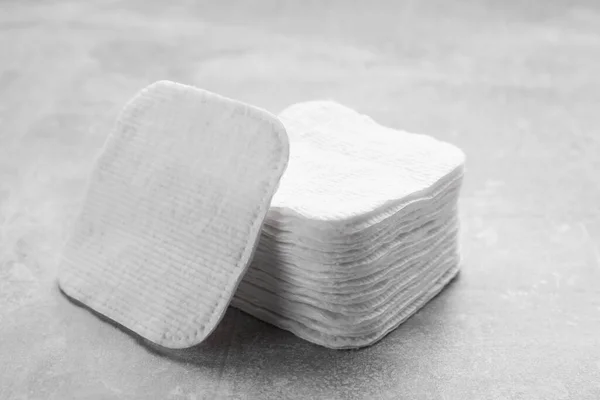 Stack of clean cotton pads on light grey table, closeup