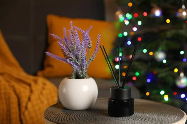 Aromatic reed air freshener and lavender on side table in cozy room