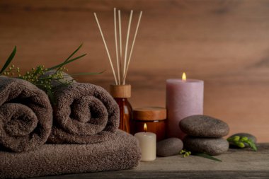 Farklı bakım ürünleri ve ahşap masada yanan mumlarla güzel bir spa kompozisyonu.