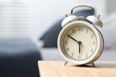 Yatak odasındaki ahşap komodindeki beyaz alarm saati, mesaj için yer.