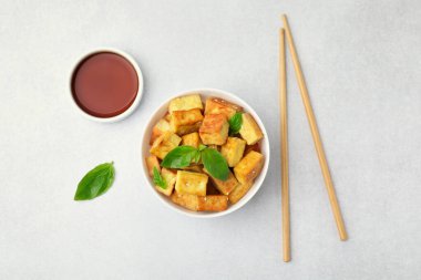 Lezzetli kızarmış tofu, fesleğen ve susam tohumları açık gri masada servis edilir.