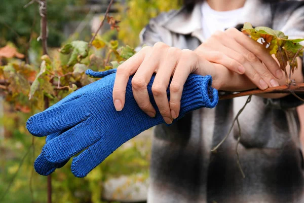 Woman holding blue protective gloves in garden, closeup