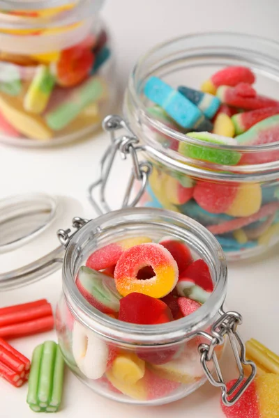Tasty jelly candies in jars on white table