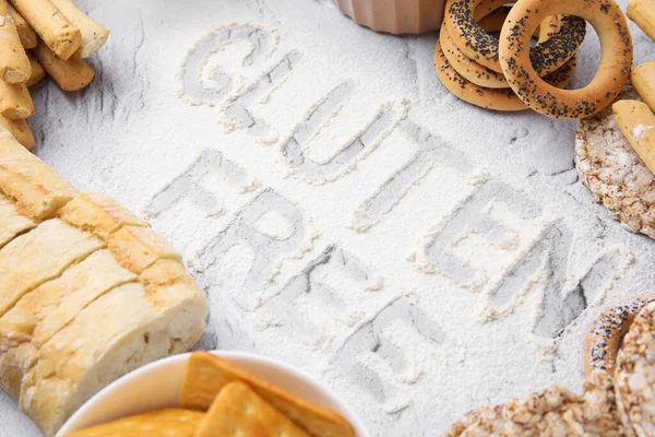 Different products and phrase Gluten free written with flour on light grey table