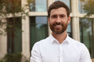 Portrait of handsome bearded man on city street, space for text