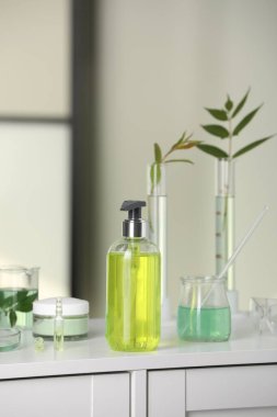 Beyaz laboratuvar çekmecesinde yaprakları olan şişe ve cam tüpler.