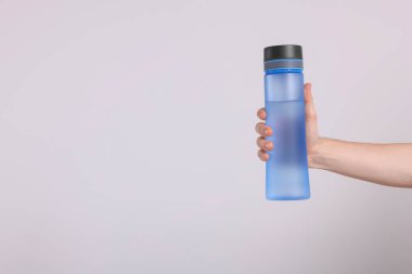 Açık gri arka planda içkili şeffaf plastik şişe tutan adam, yakın plan. Metin için boşluk