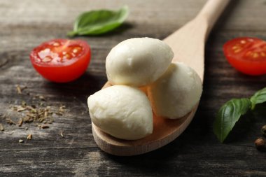 Nefis mozarella topları, domatesler ve fesleğen yaprakları ahşap masada, yakın plan.
