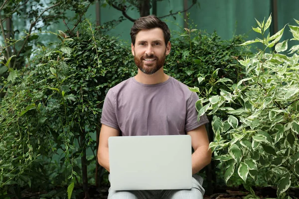 Handsome man with laptop in green garden