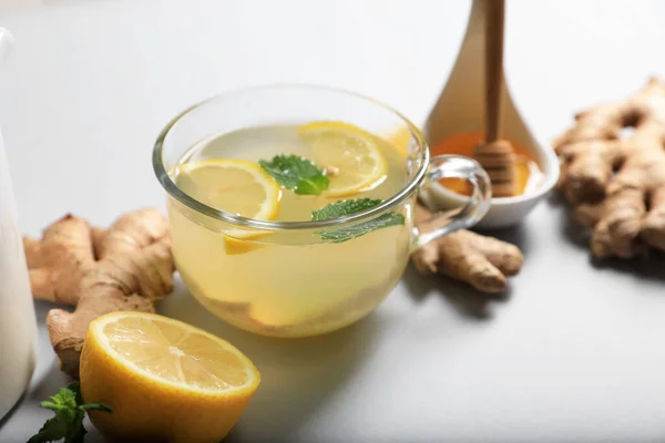 Delicious ginger tea and ingredients on light grey background