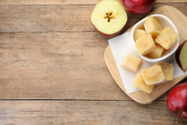 Frozen apple puree cubes and ingredient on wooden table, flat lay. Space for text