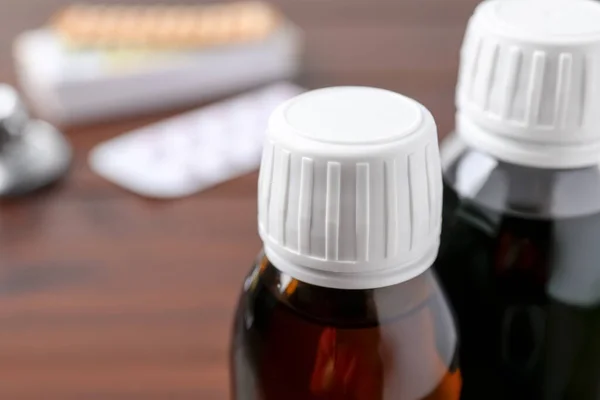Bottles of syrup on wooden table, closeup with space for text. Cold medicine