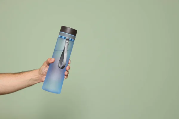 男人拿着透明的塑料瓶水在浅绿色的背景上 案文的篇幅 — 图库照片