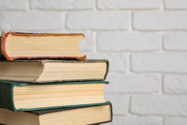 Beyaz tuğla duvarın yanında bir sürü eski ciltli kitap, yakın plan. Metin için boşluk