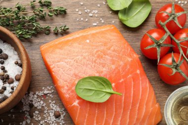 Taze çiğ somon ve ahşap masada terbiye edilecek malzemeler.