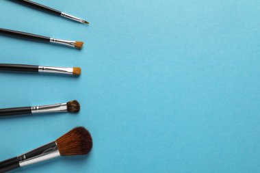 Açık mavi arka planda düz bir makyaj fırçası seti. Metin için boşluk