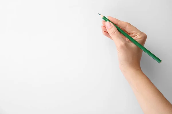 Woman with green pencil on white background, closeup. Space for text