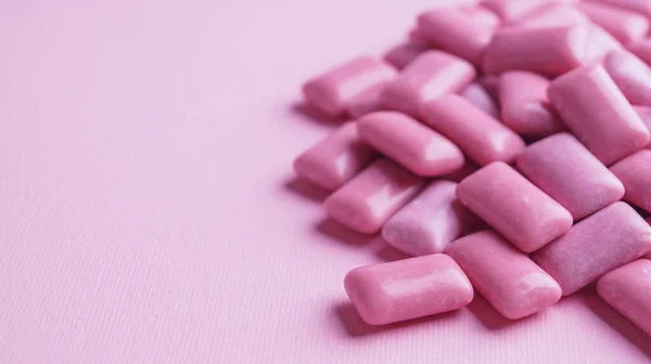 Heap of tasty sweet chewing gums on pink background, closeup. Space for text