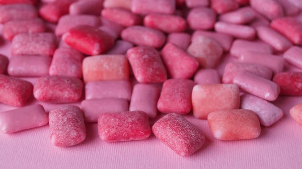Many sweet chewing gums on pink background, closeup
