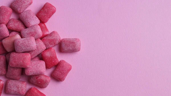 Heap of tasty sweet chewing gums on pink background, flat lay. Space for text