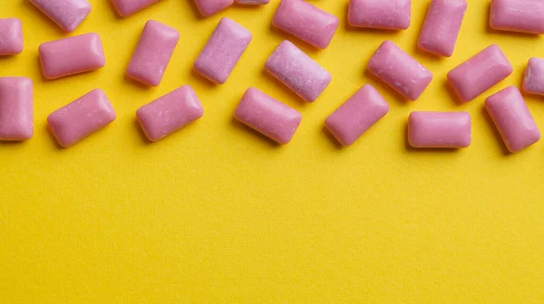 Sweet chewing gums on yellow background, flat lay. Space for text
