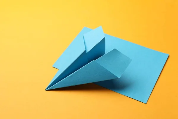 Handmade light blue plane and piece of paper on yellow background