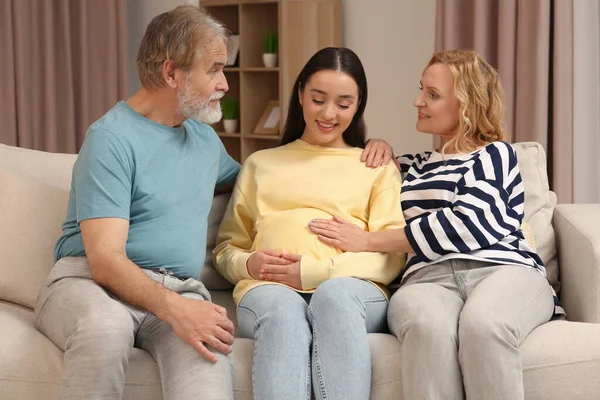 Happy pregnant woman spending time with her parents at home. Grandparents\' reaction to future grandson