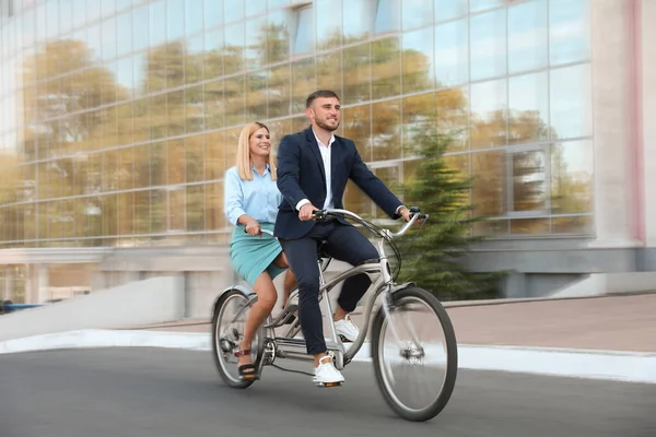 Couple riding tandem bike on city street, motion blur effect