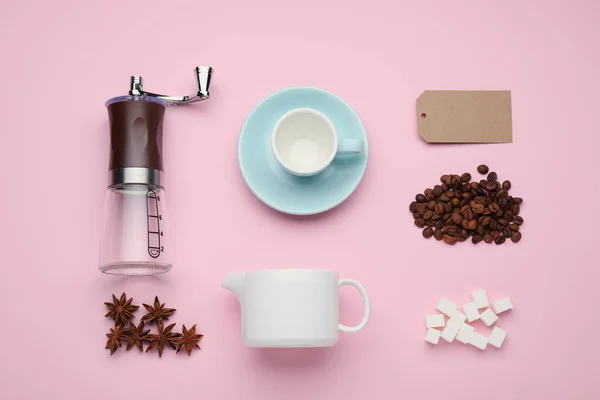 Flat lay composition with manual coffee grinder and beans on pink background