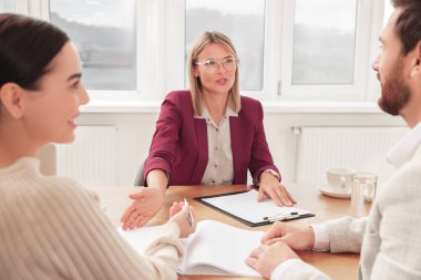 Emlakçı ve çift yeni dairedeki masada sözleşme imzalıyorlar.
