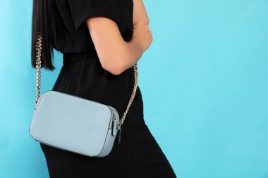 Açık mavi arka planda şık çantalı bir kadın, yakın plan. Metin için boşluk