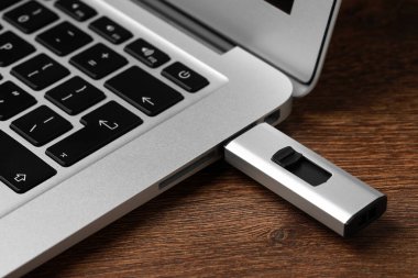 USB flaş bellek ahşap masadaki dizüstü bilgisayara bağlı, yakın plan.